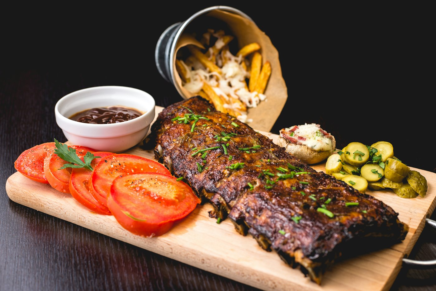 Costela assada servida na tábua com tomates e acompanhamentos